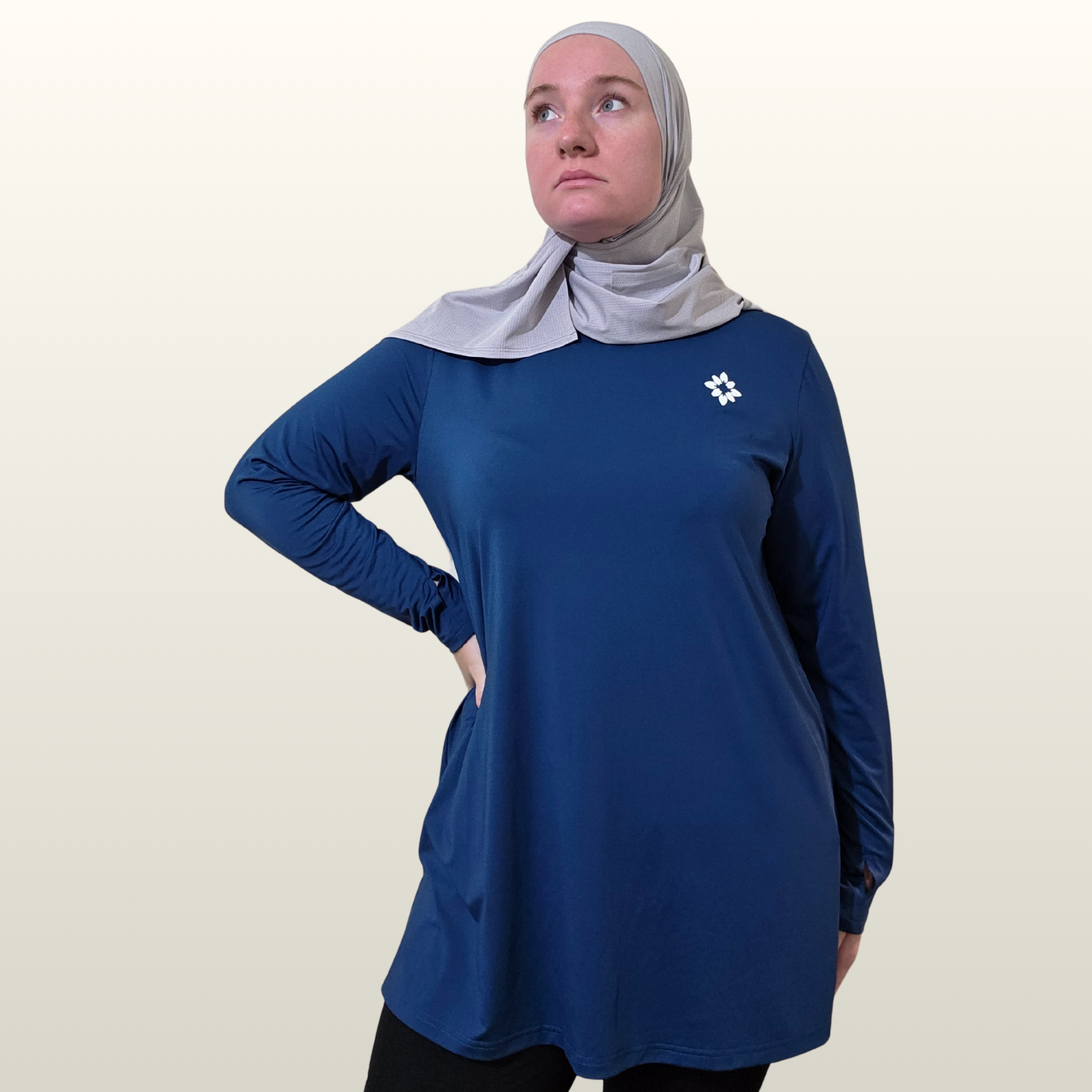 Woman wearing a blue long-sleeve shirt with a logo on a beige background